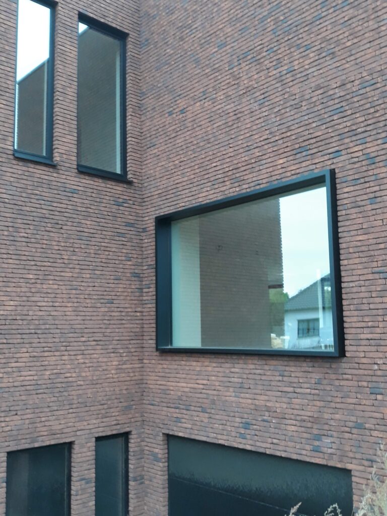 Aluminium raam met brede glaspartij in een donkere bakstenen gevel