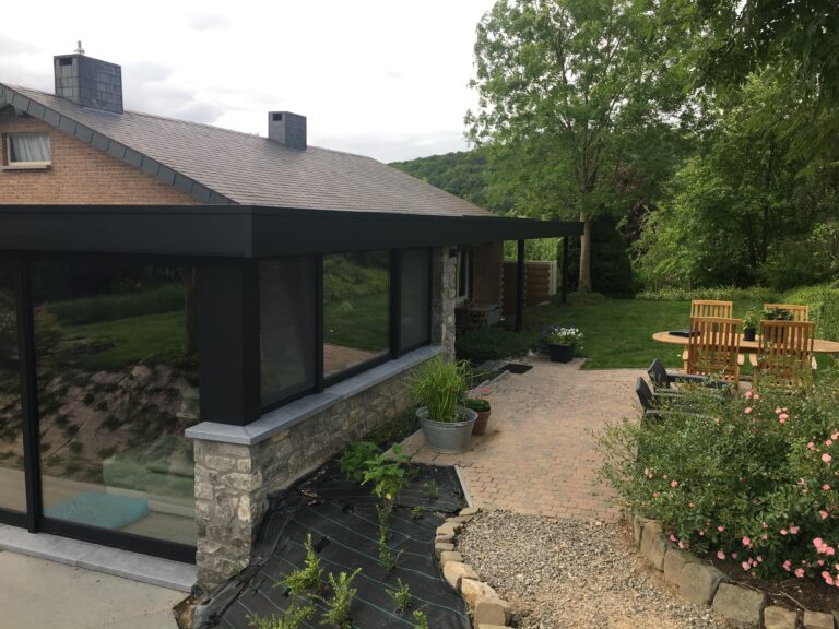 Aluminium glaspartijen aan een tuinkamer met natuurstenen muur