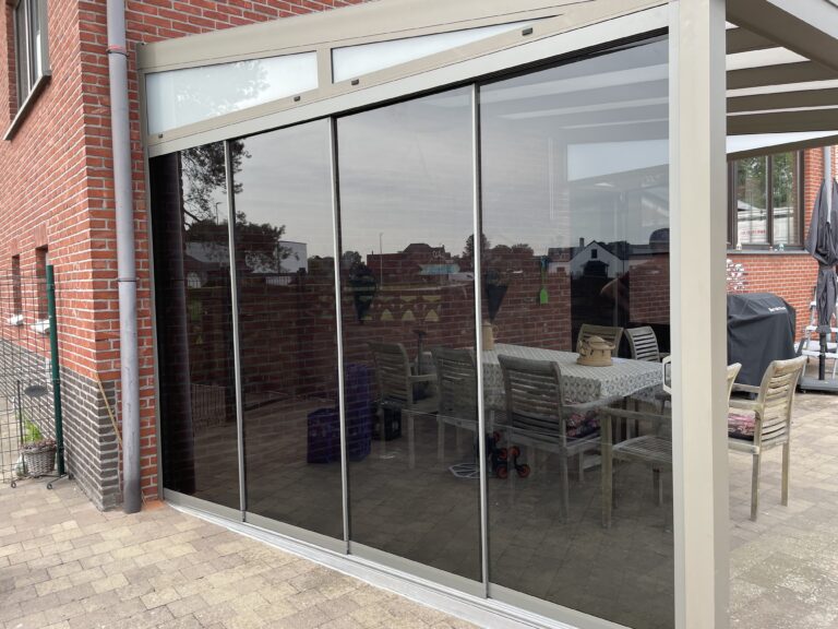 Glazen schuifwanden onder een terrasoverkapping aan een bakstenen woning