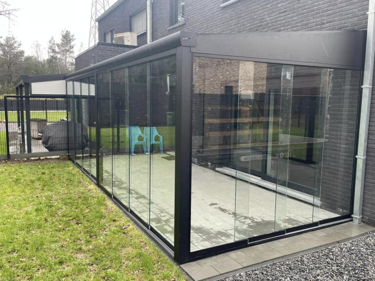 Glazen schuifwanden onder een zwarte overkapping in de tuin