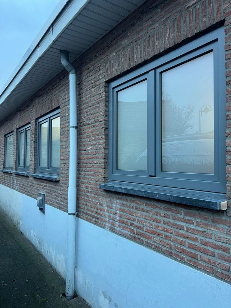 Kwartsgrijze PVC ramen in een bakstenen gevel